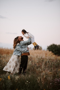 man and woman kissing on brown grass field during daytime