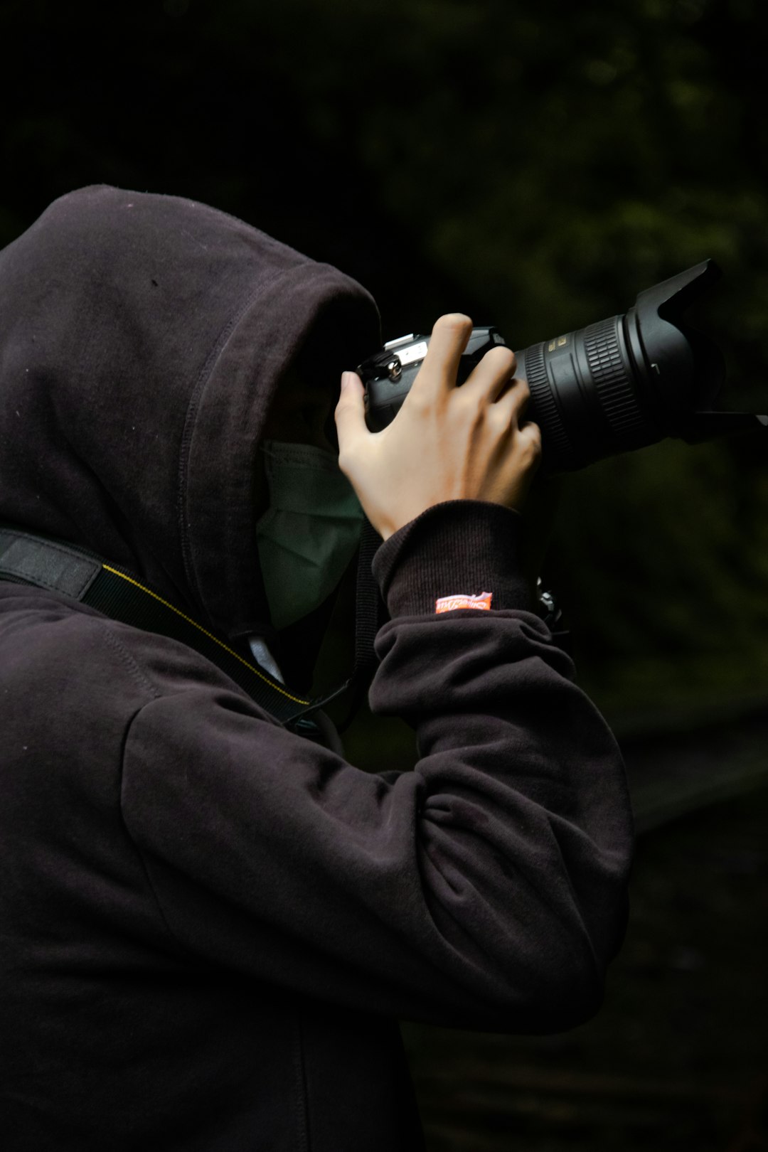 man in black hoodie using black dslr camera