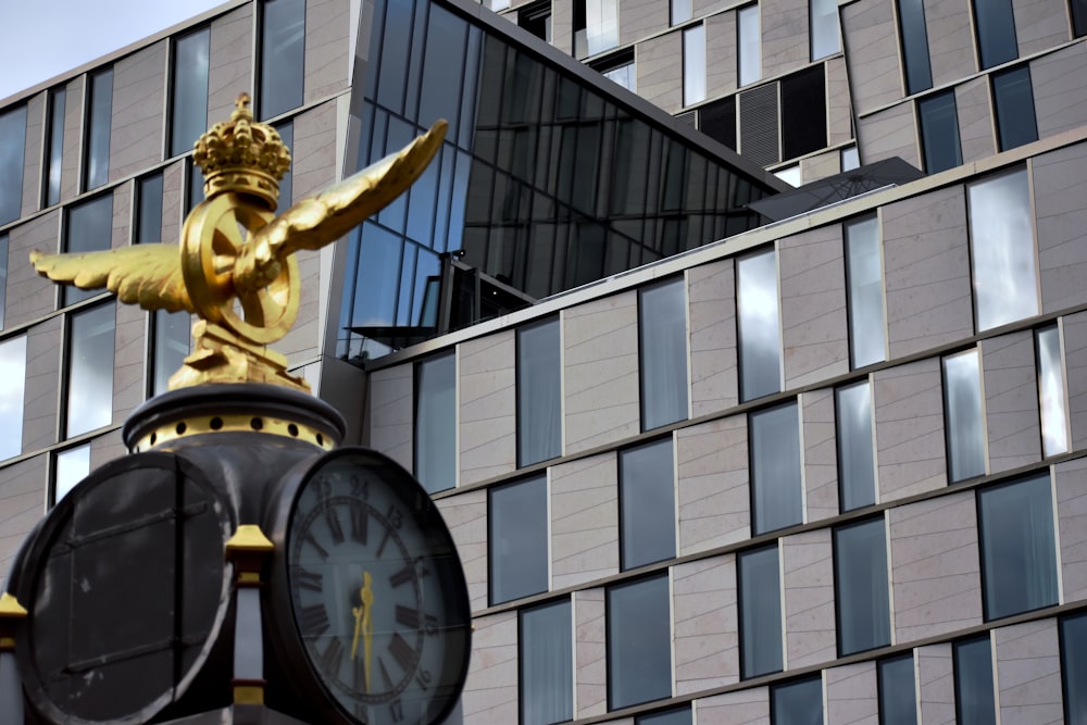 gold statue near glass building during daytime