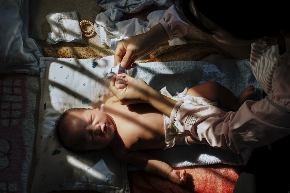 baby lying on bed holding white plastic toy