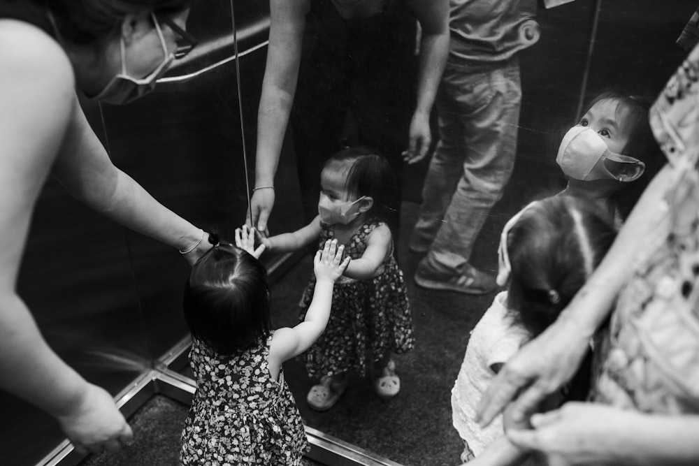 grayscale photo of woman in dress carrying baby