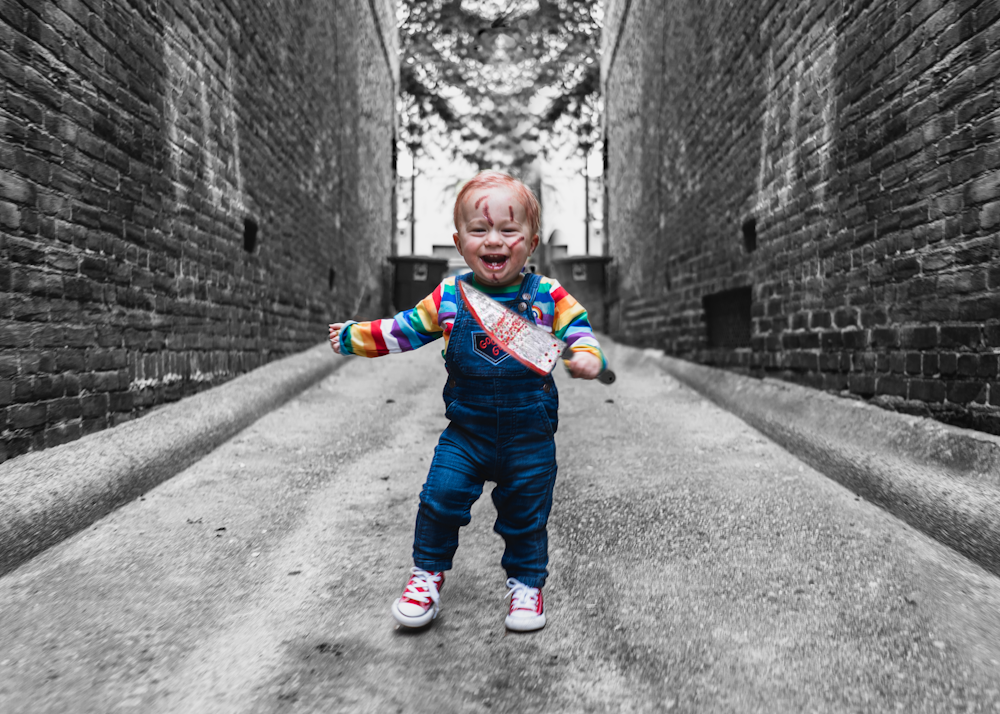 grayscale photo of child in red and blue jacket and pants