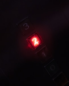 Elevator control panel showing an emergency rescue button illuminated in red.