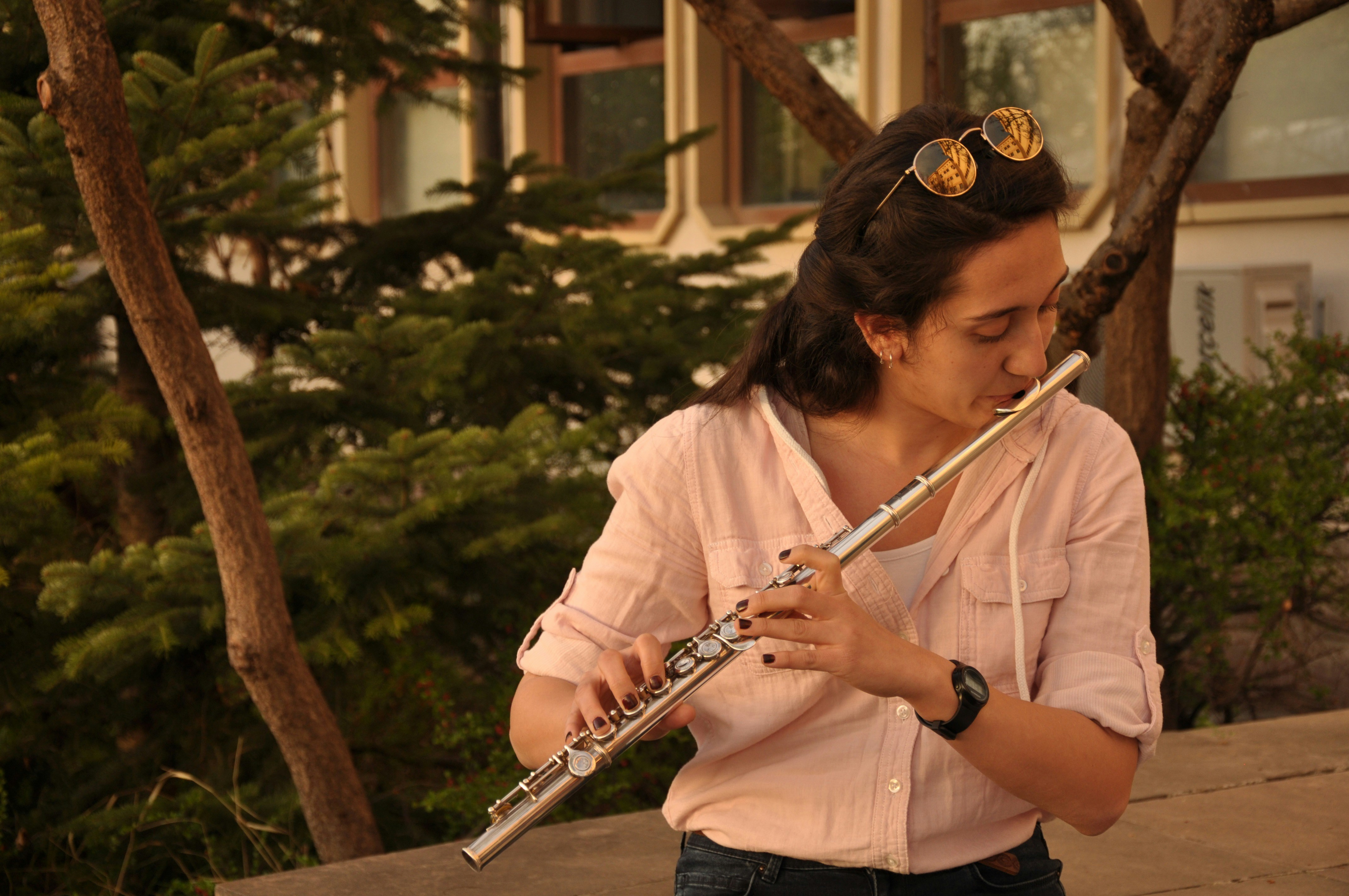 woman in white shirt playing flute flute teams background