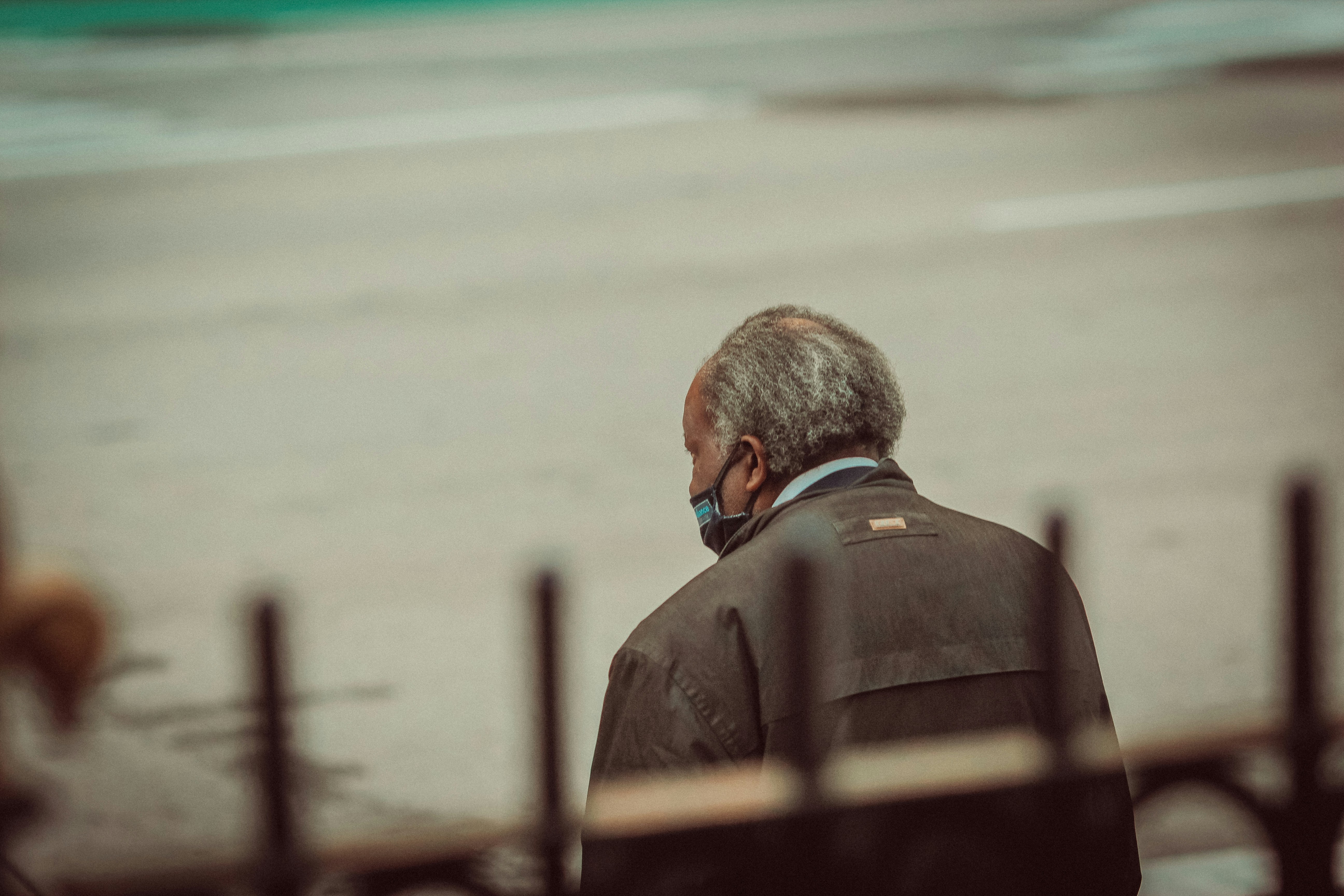 man in brown coat standing on beach during daytime