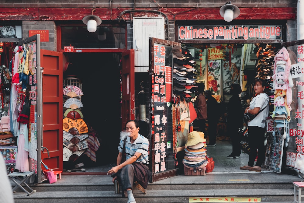 man in black jacket sitting on sidewalk during daytime