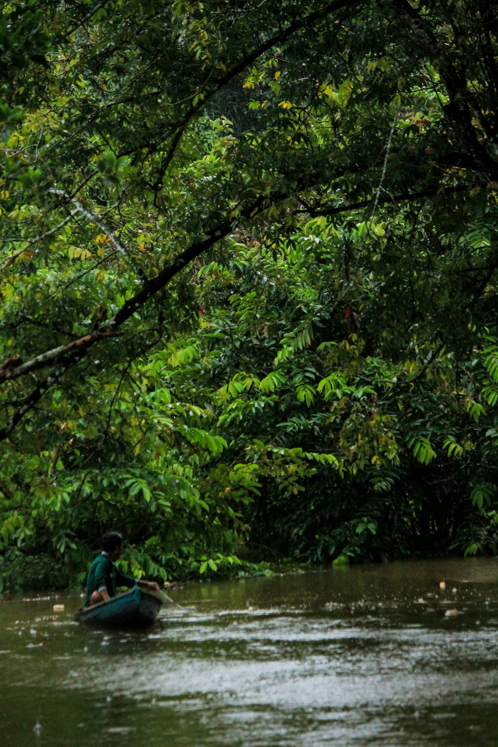 man in blue shirt riding on blue kayak on river during daytime