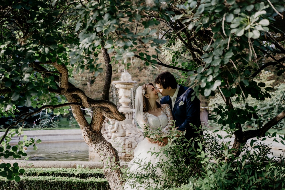 man and woman kissing under tree