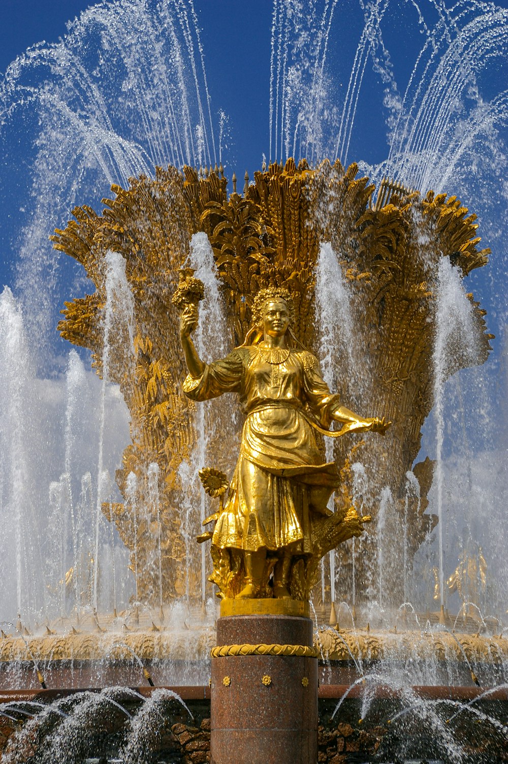gold statue of man with water fountain in the middle