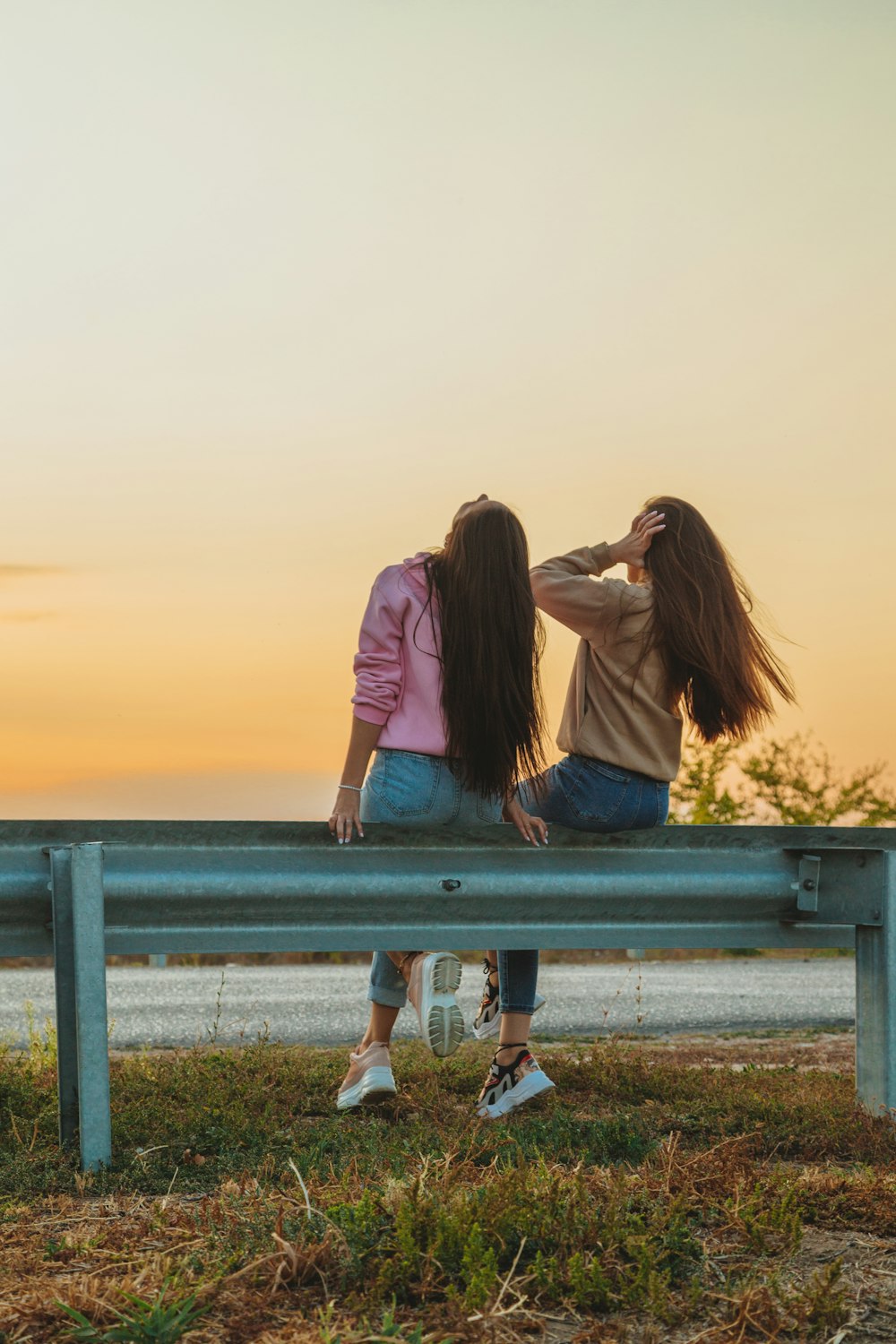 2 women sitting on bench during daytime