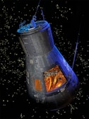 A spacecraft capsule is floating in space against a backdrop of distant stars. The capsule is sleek with visible panels and structure, showing an interior filled with complex machinery and tubing. The light inside the capsule creates a warm, orange glow contrasting with the cold, dark space outside.