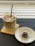 A glass of iced coffee with a straw sits on a wooden coaster, accompanied by a small chocolate-covered treat with coconut shavings on a white dish. The background features a striped pattern, creating a cozy and inviting atmosphere.
