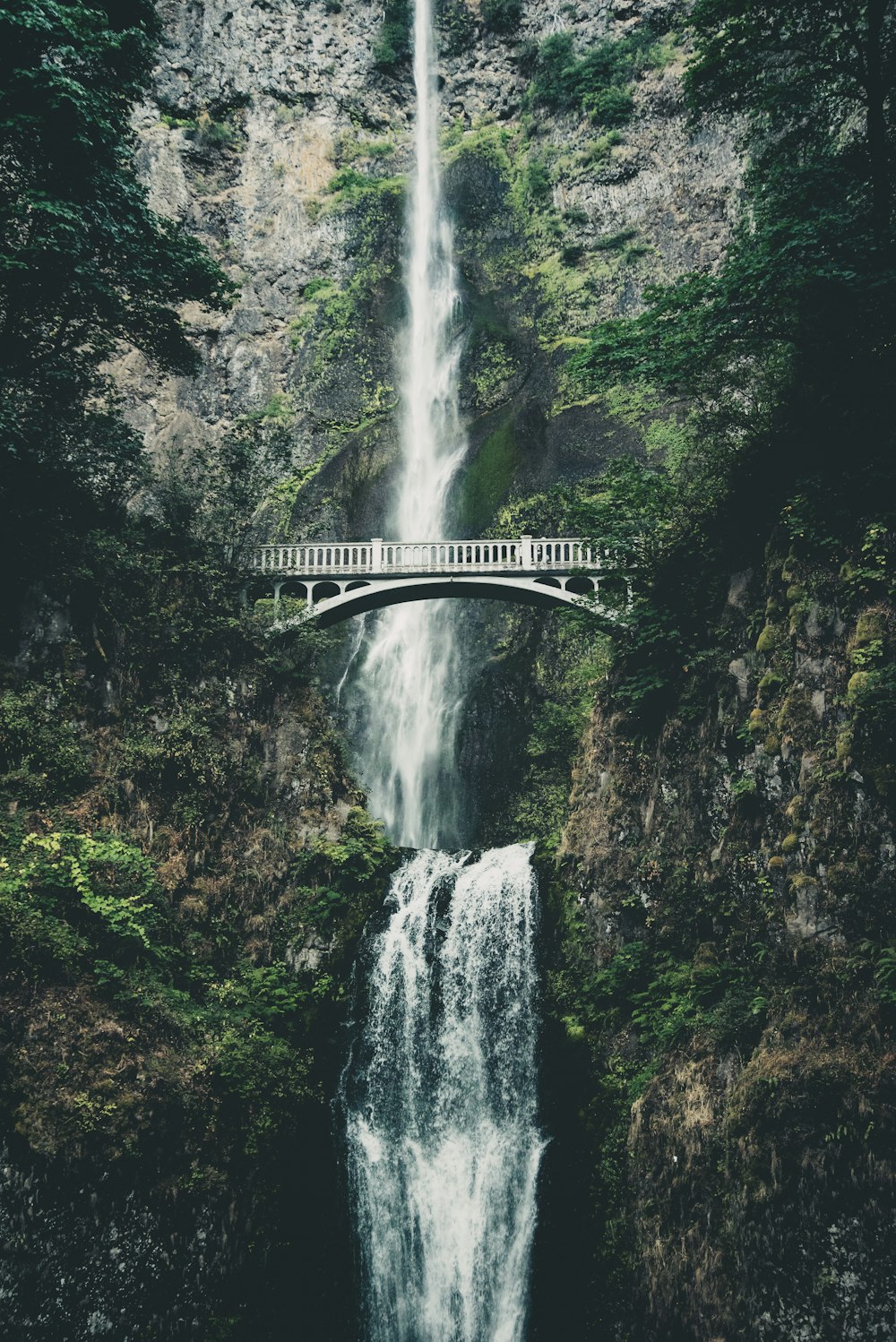 white bridge over waterfalls during daytime