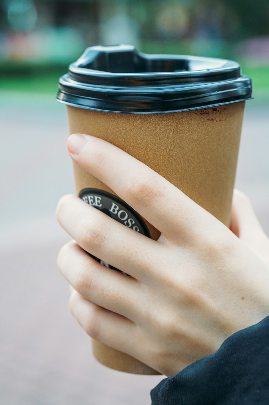 person holding brown and black coffee cup