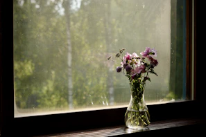 Sunlight streaming over a handmade teal vase filled with fresh wildflowers on a windowsill