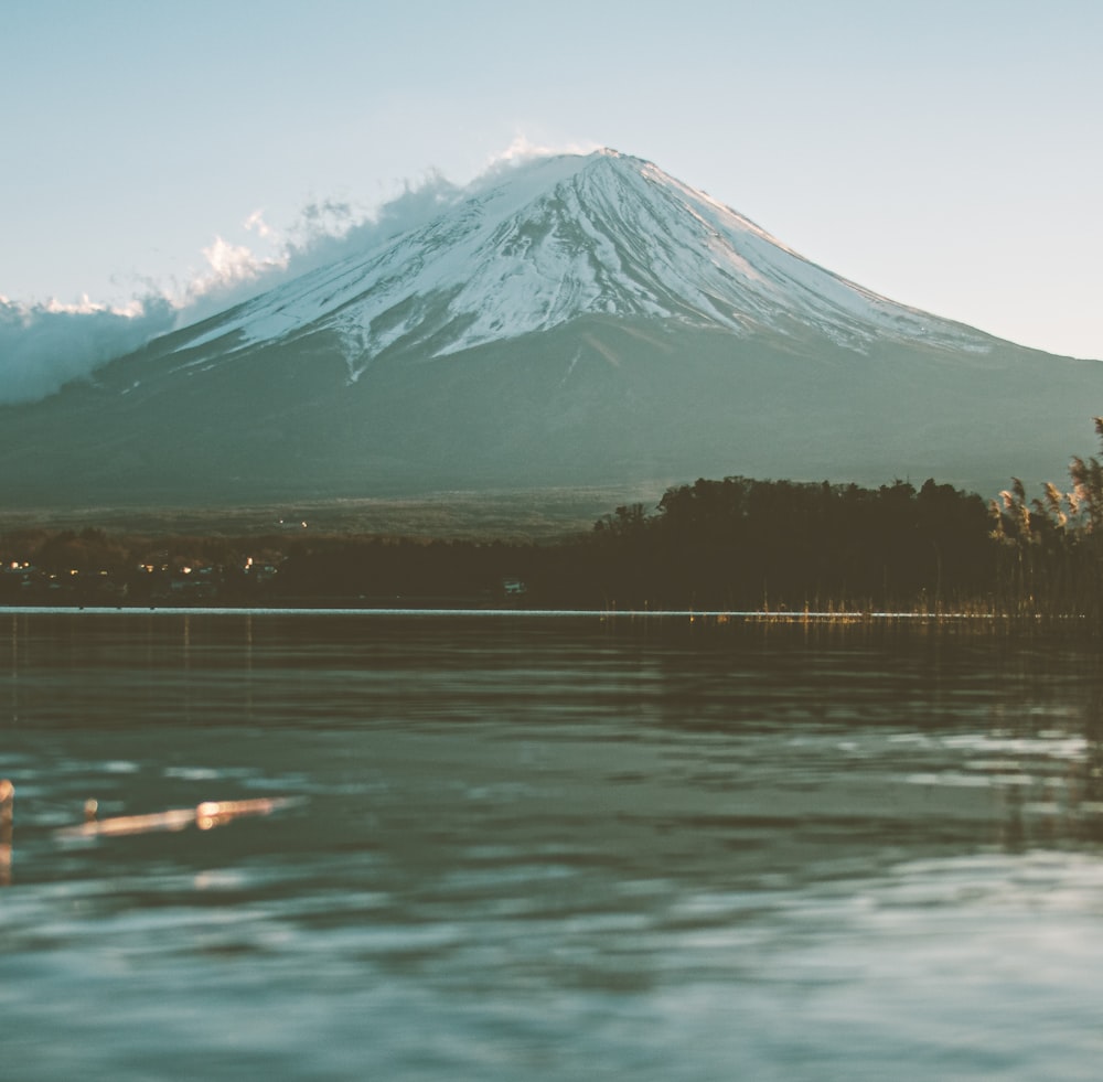 snow covered mountain near body of water during daytime