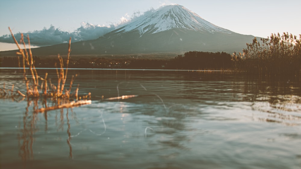 snow covered mountain near body of water during daytime