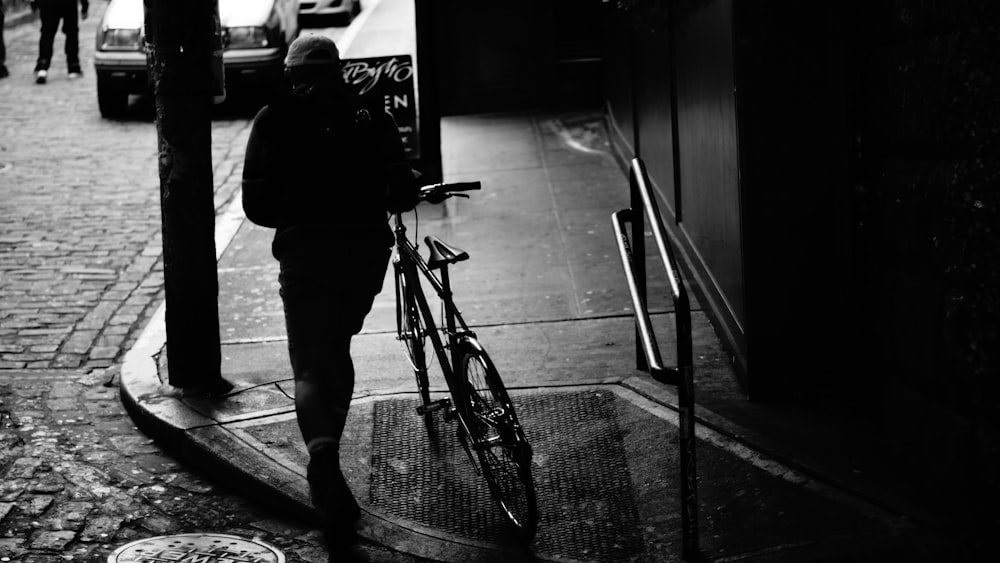 man in black jacket and pants standing beside bicycle
