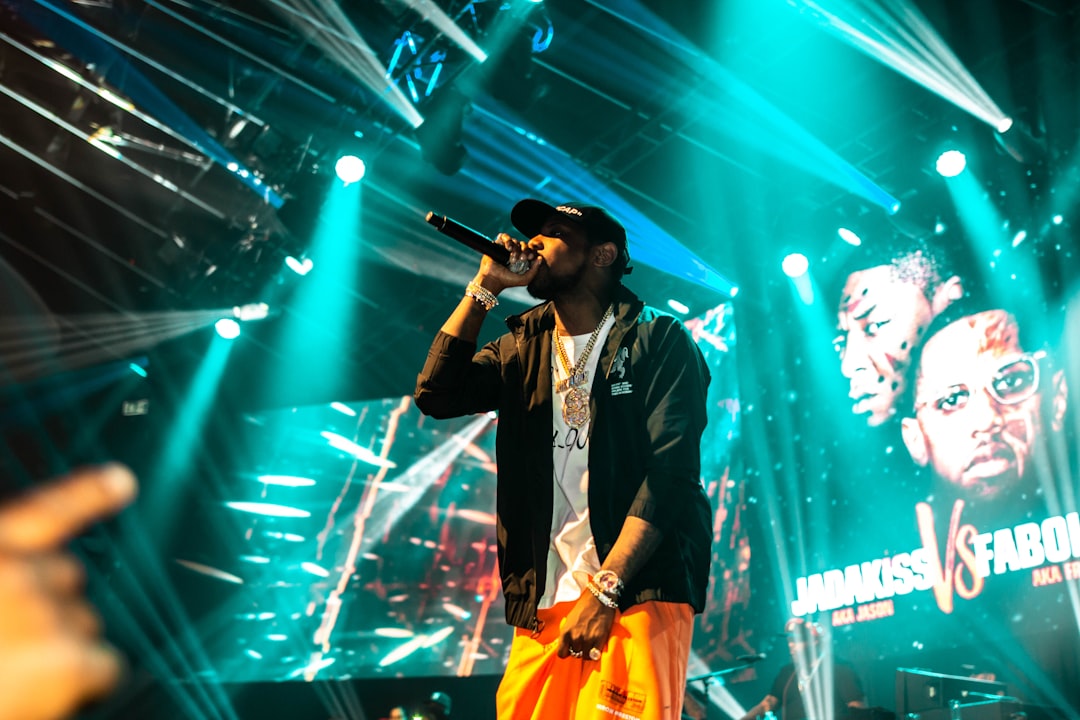 man in black blazer and yellow pants singing on stage