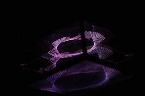 A close-up of intricate geometric patterns glowing with neon light against a dark background.