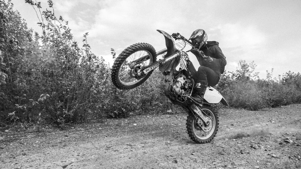 grayscale photo of man riding motocross dirt bike