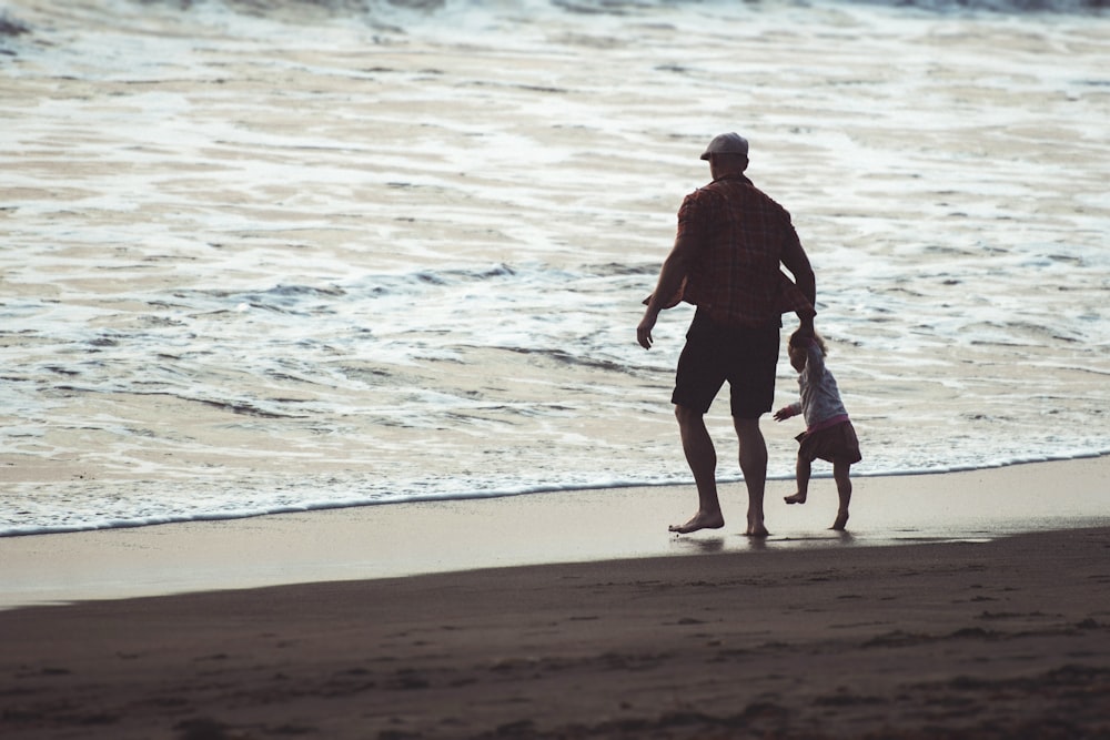 man in black shirt walking on beach during daytime