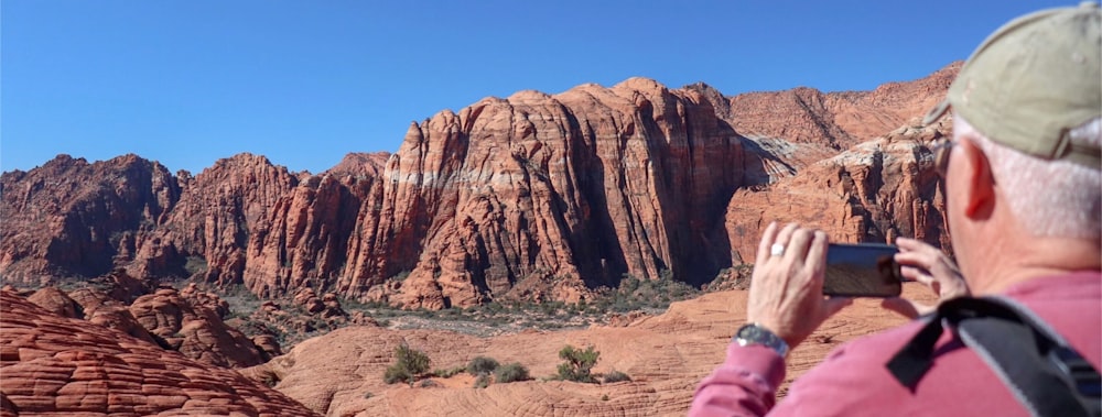 woman in pink jacket standing near brown rock formation during daytime