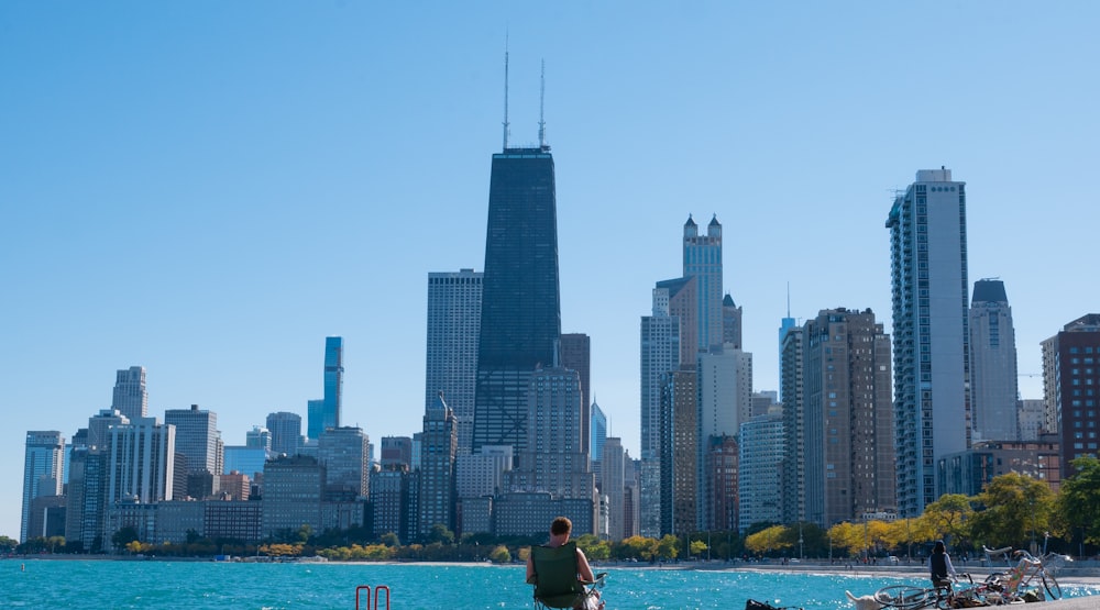 man and woman sitting on boat on water near city buildings during daytime