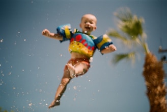Smiling children in colorful swim gear learning to float and splash in a bright indoor pool.