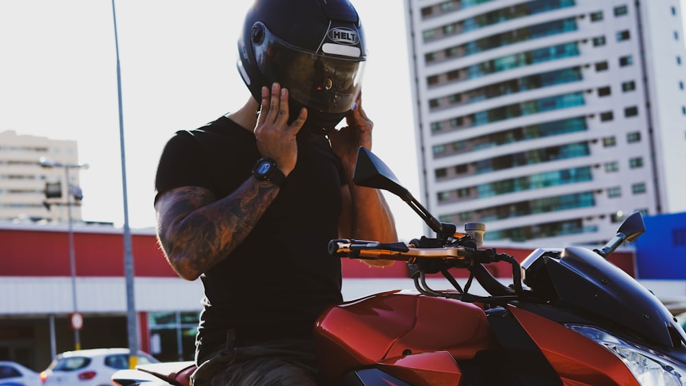 man in black t-shirt and helmet riding red motorcycle