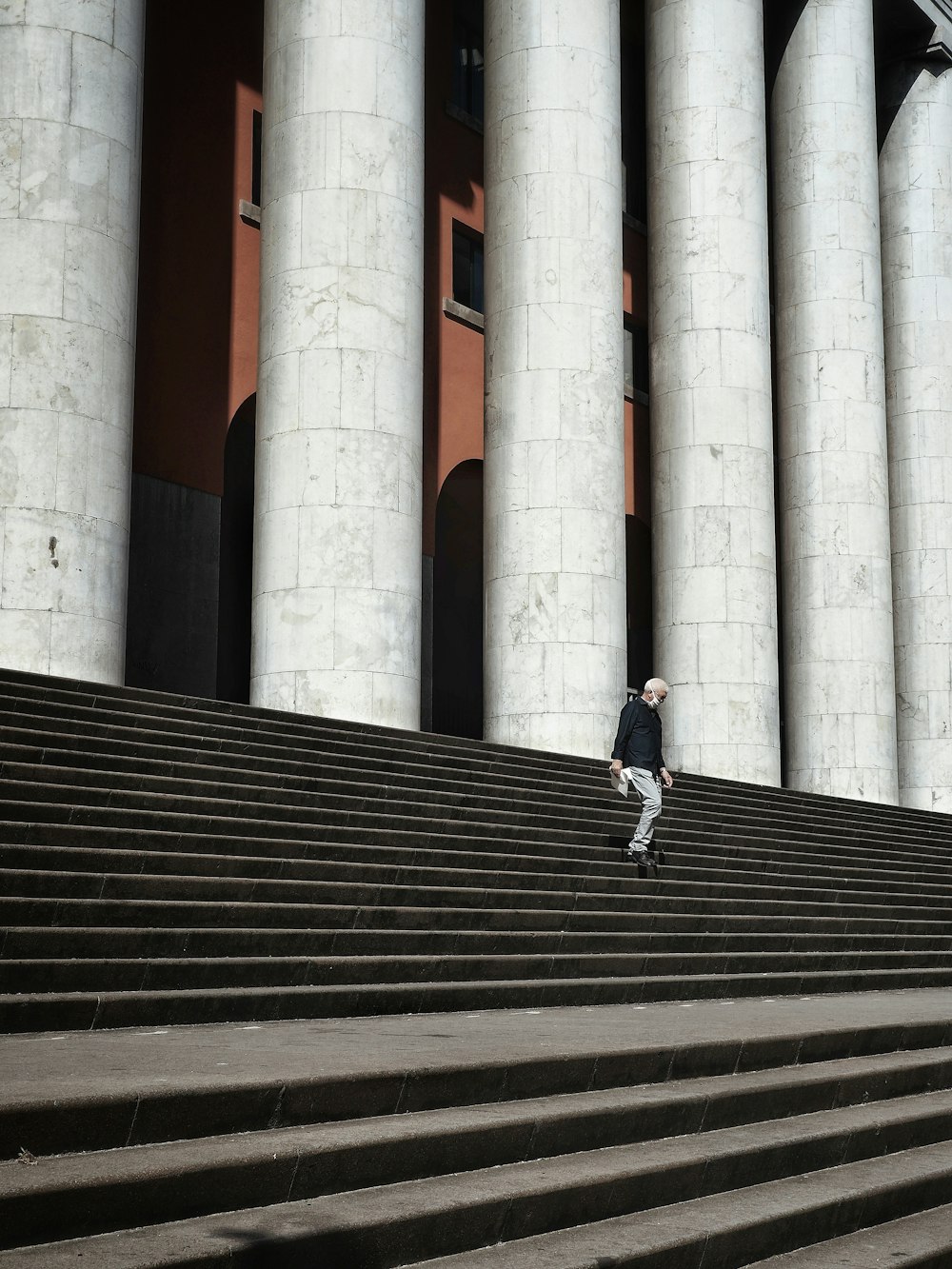 man in blue jacket and blue denim jeans walking on gray concrete stairs