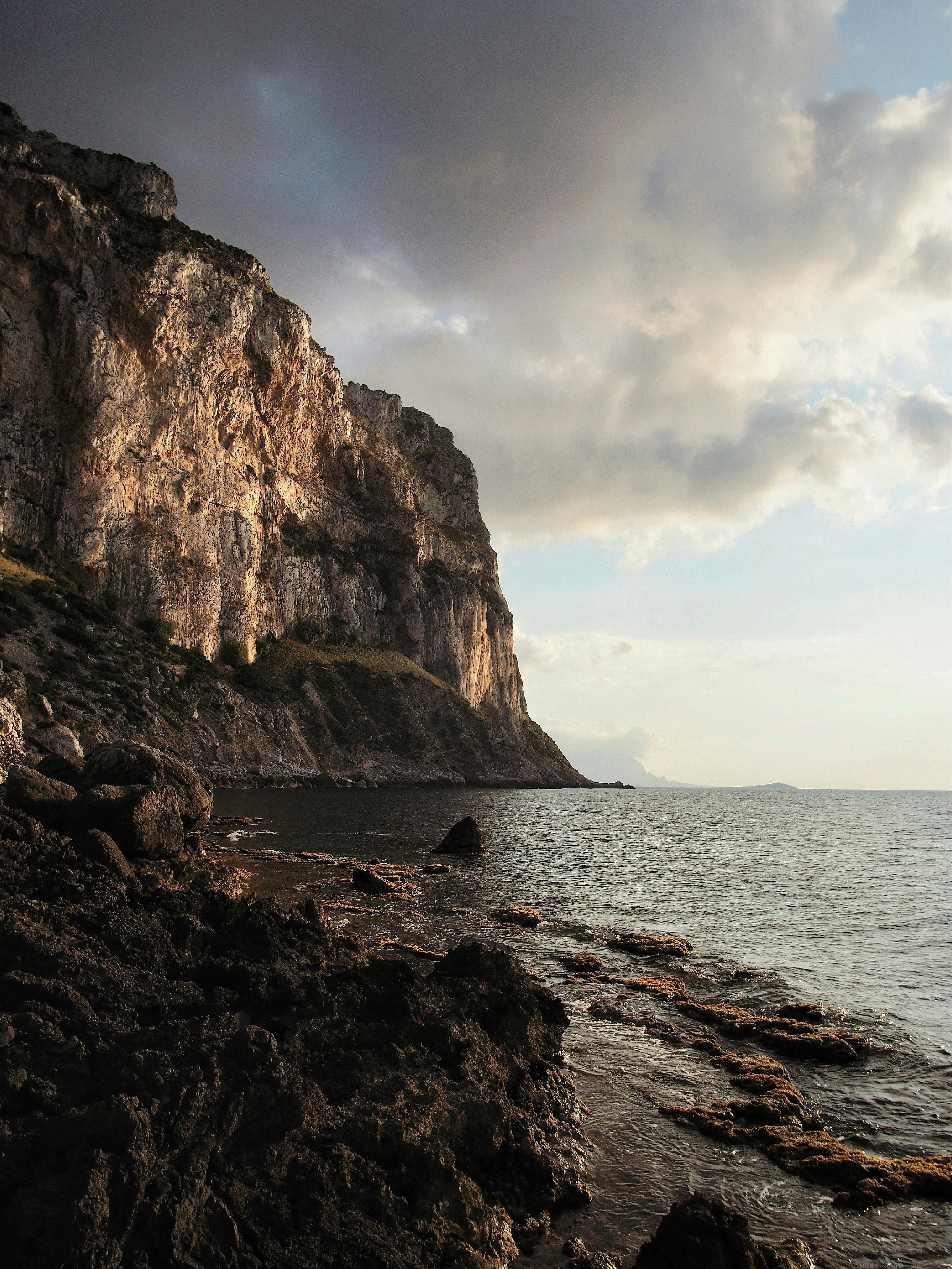 a rocky beach with a large cliff in the background