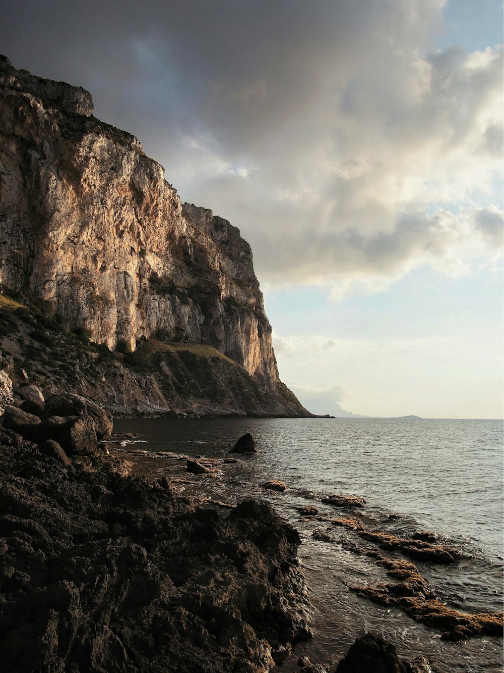 a rocky beach with a large cliff in the background
