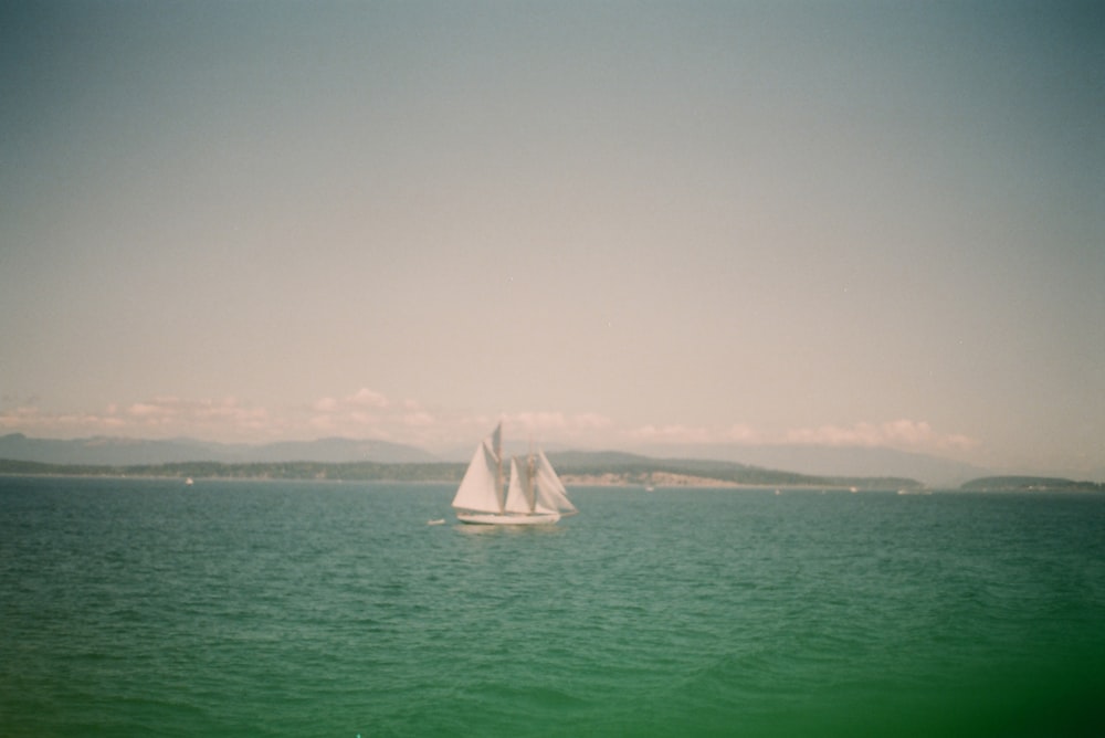 white sailboat on sea under white sky during daytime