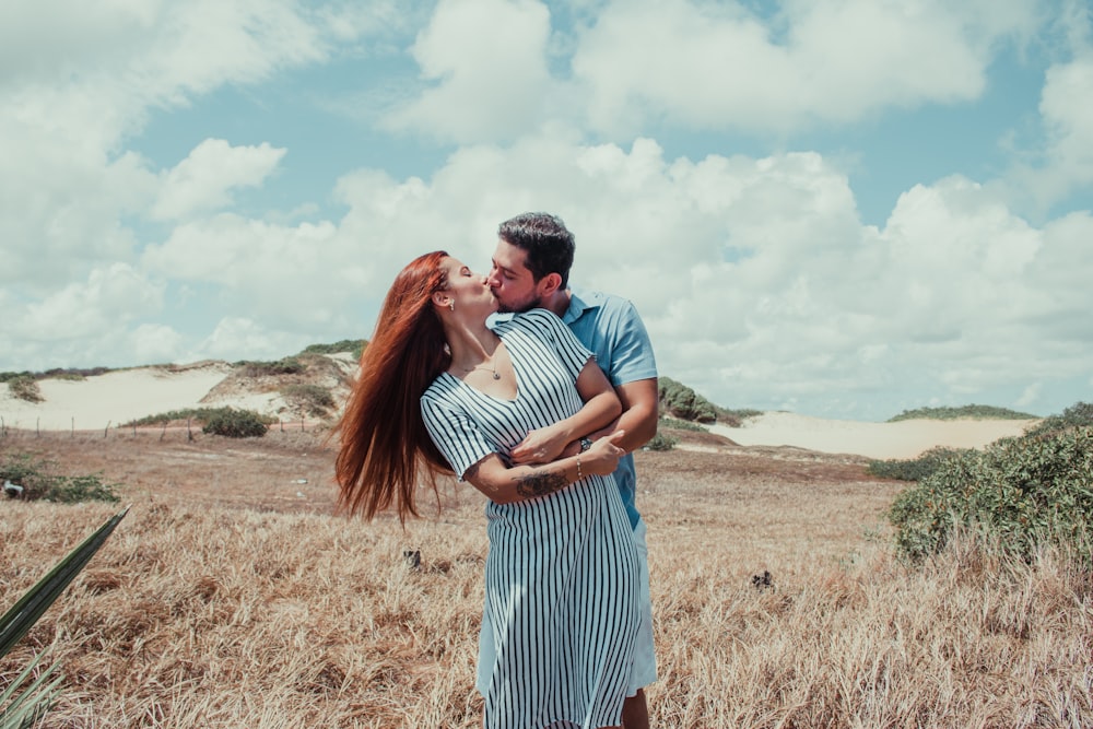 man and woman kissing on brown field during daytime