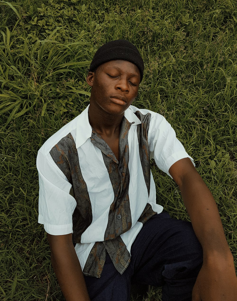 man in white button up shirt and black pants sitting on green grass during daytime