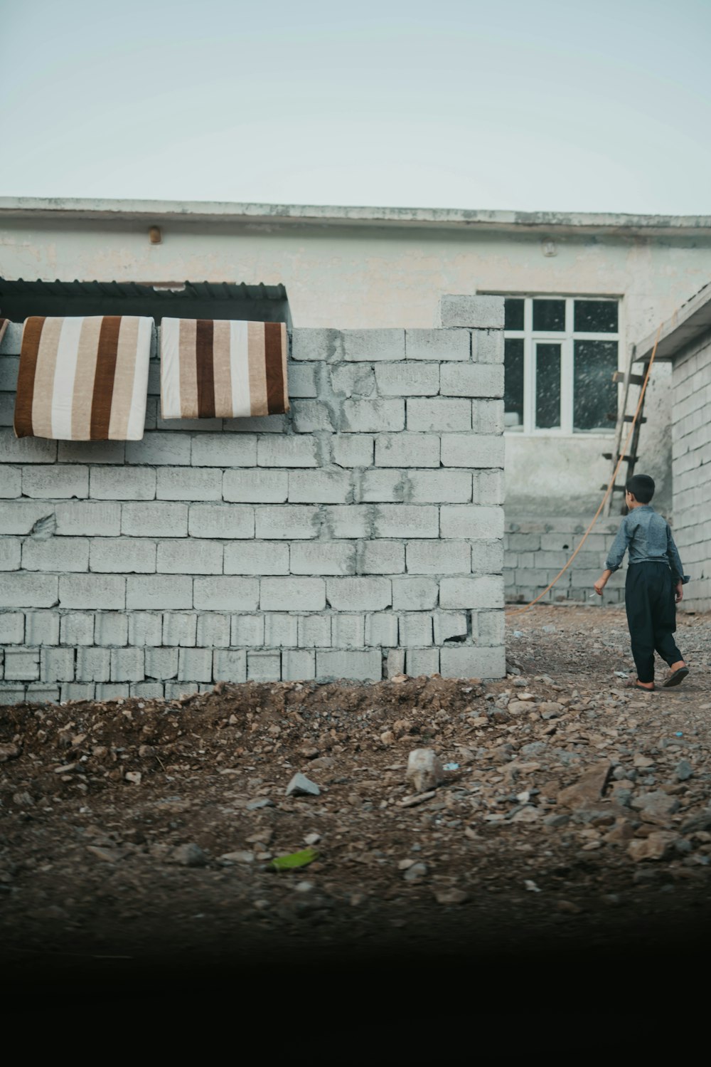 woman in black jacket walking beside white brick wall during daytime