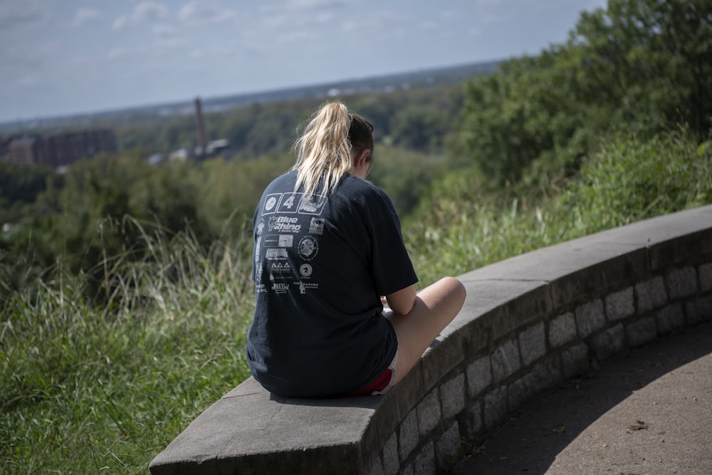 woman in black t-shirt sitting on concrete bench during daytime