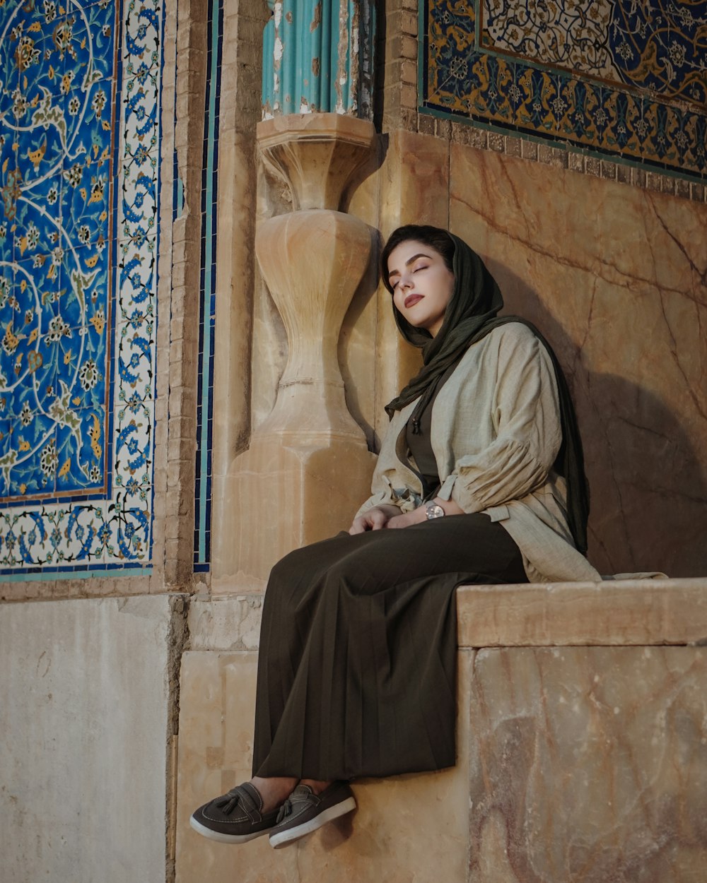 Mujer con hiyab negro sentada en un banco de hormigón marrón