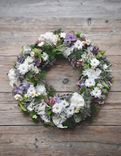 Soft cream and green floral wreath resting gently on a polished wooden table.