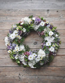 Soft cream and green floral wreath resting gently on a polished wooden table.