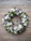 A serene funeral wreath arrangement with soft white flowers and dark green leaves on a wooden table.