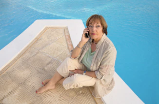 A friendly pool technician answering a phone call beside a sparkling clean pool.