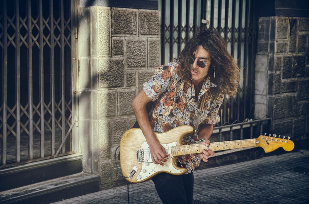 woman in white and black floral shirt playing white electric guitar