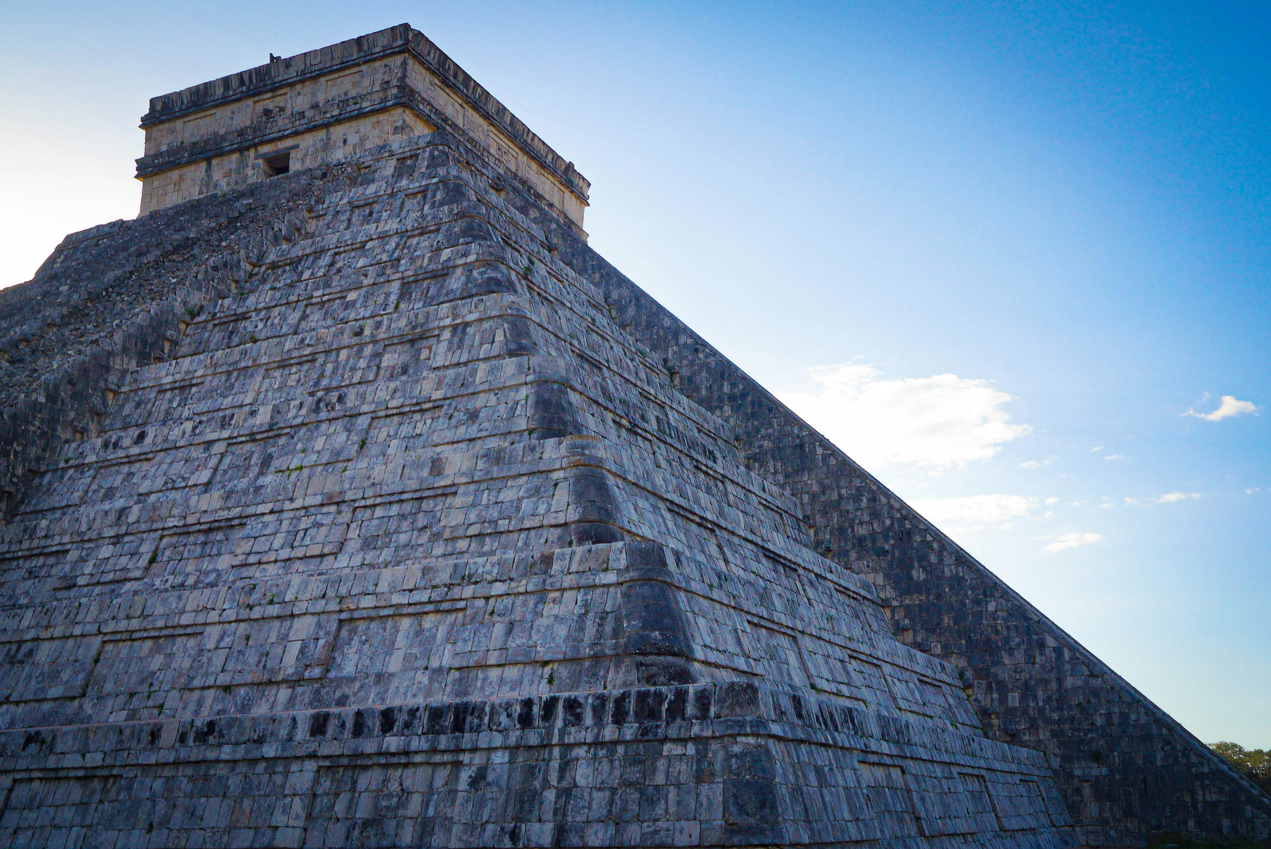 gray brick wall under blue sky during daytime mayan pyramid teams background