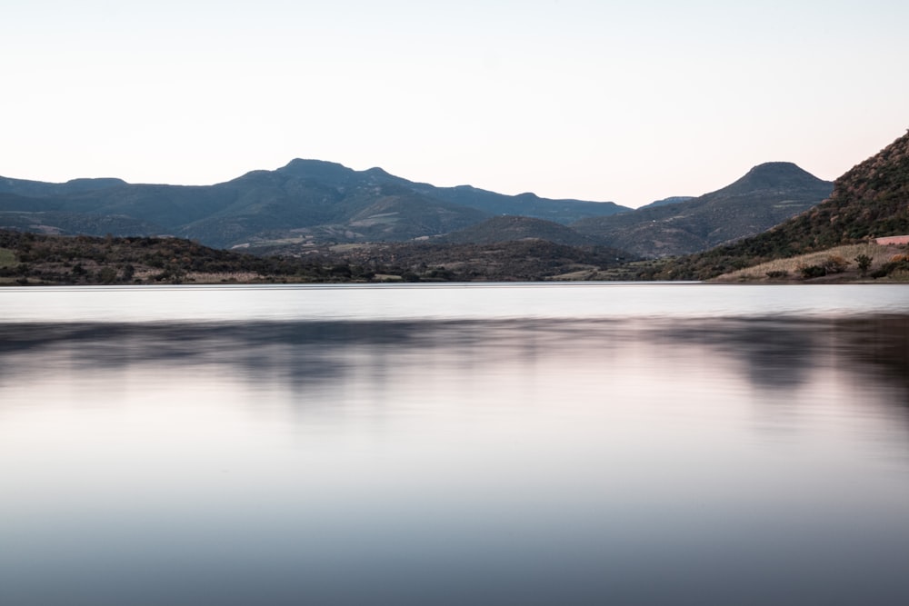 body of water near mountain during daytime