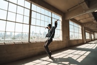 man in black t-shirt and black pants standing on brown concrete floor during daytime