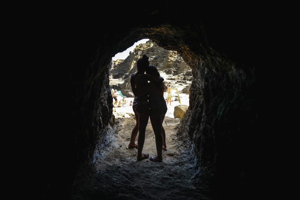 man in black jacket standing on cave