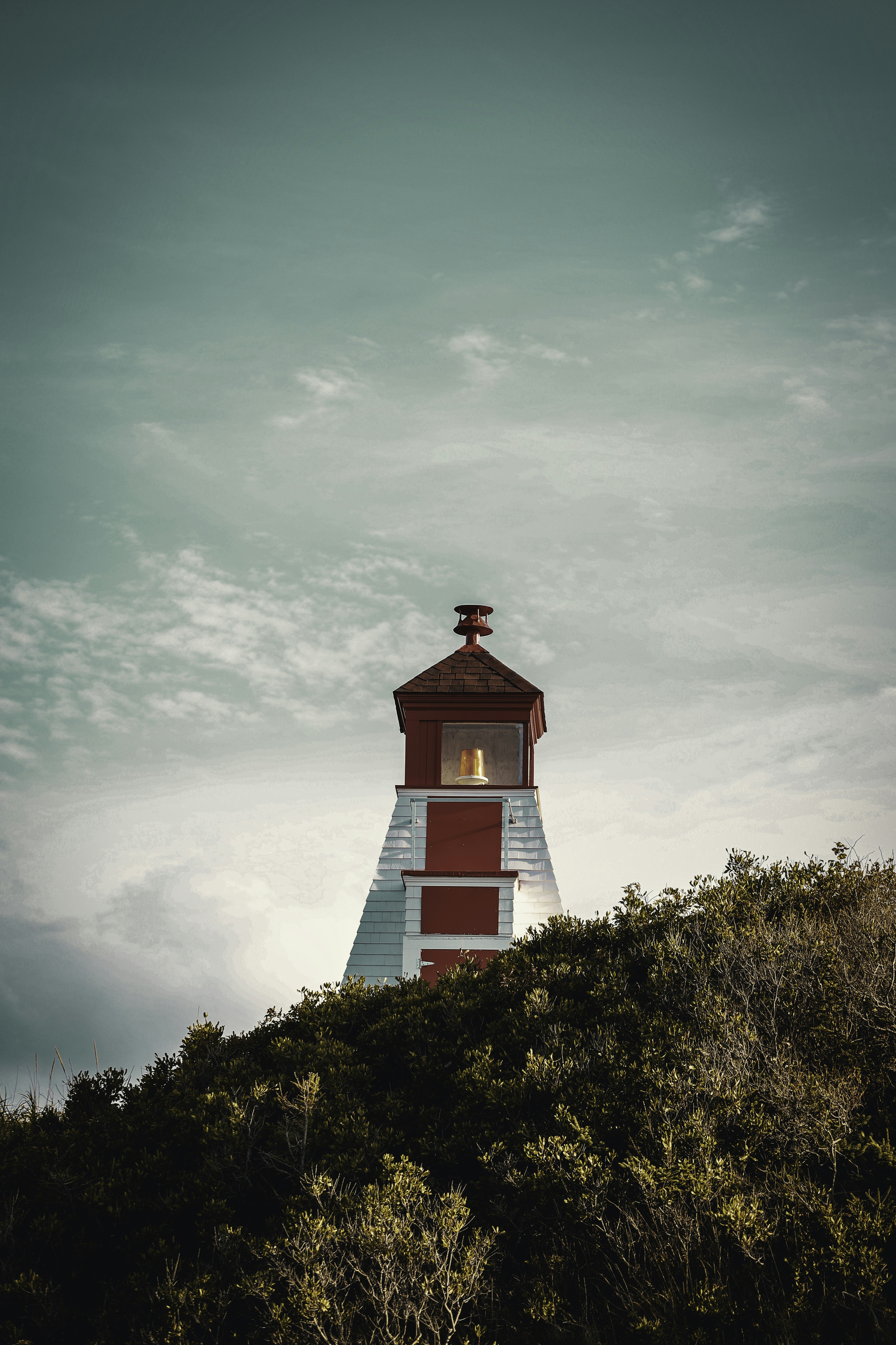 a red and white lighthouse on top of a hill