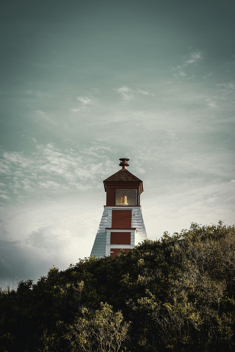 a red and white lighthouse on top of a hill